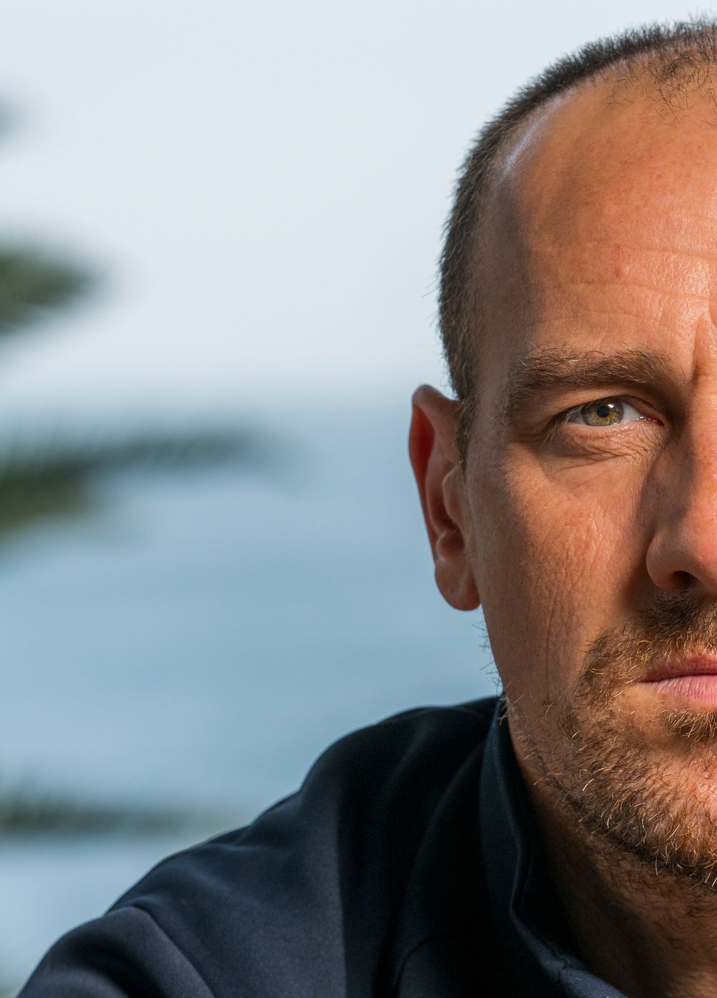 Close-up portrait against ocean background on a sunny day.