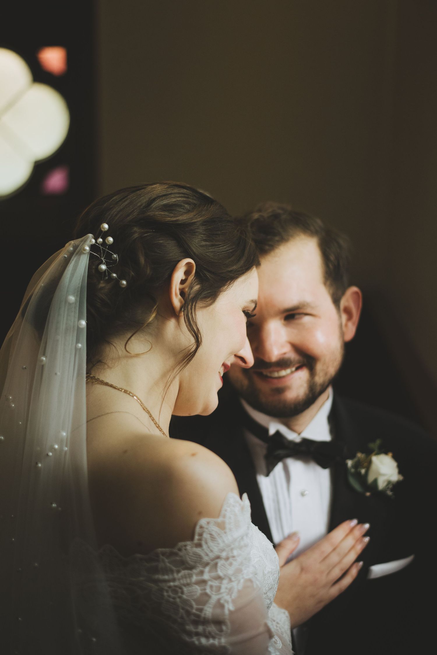 a bride and groom embrace and smile at each other in the stairwell at st andrew's cathedral. a stained glass window.