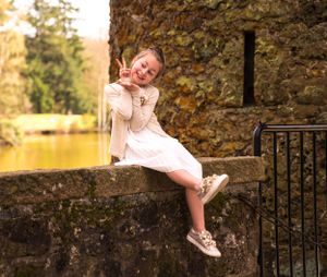 een foto van een meisje (communicant) op een muur van een kasteel in het zonlicht in een park.