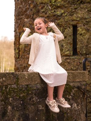 een fot van een communicant op een muurtje van een kasteel in het zonlicht in een park.