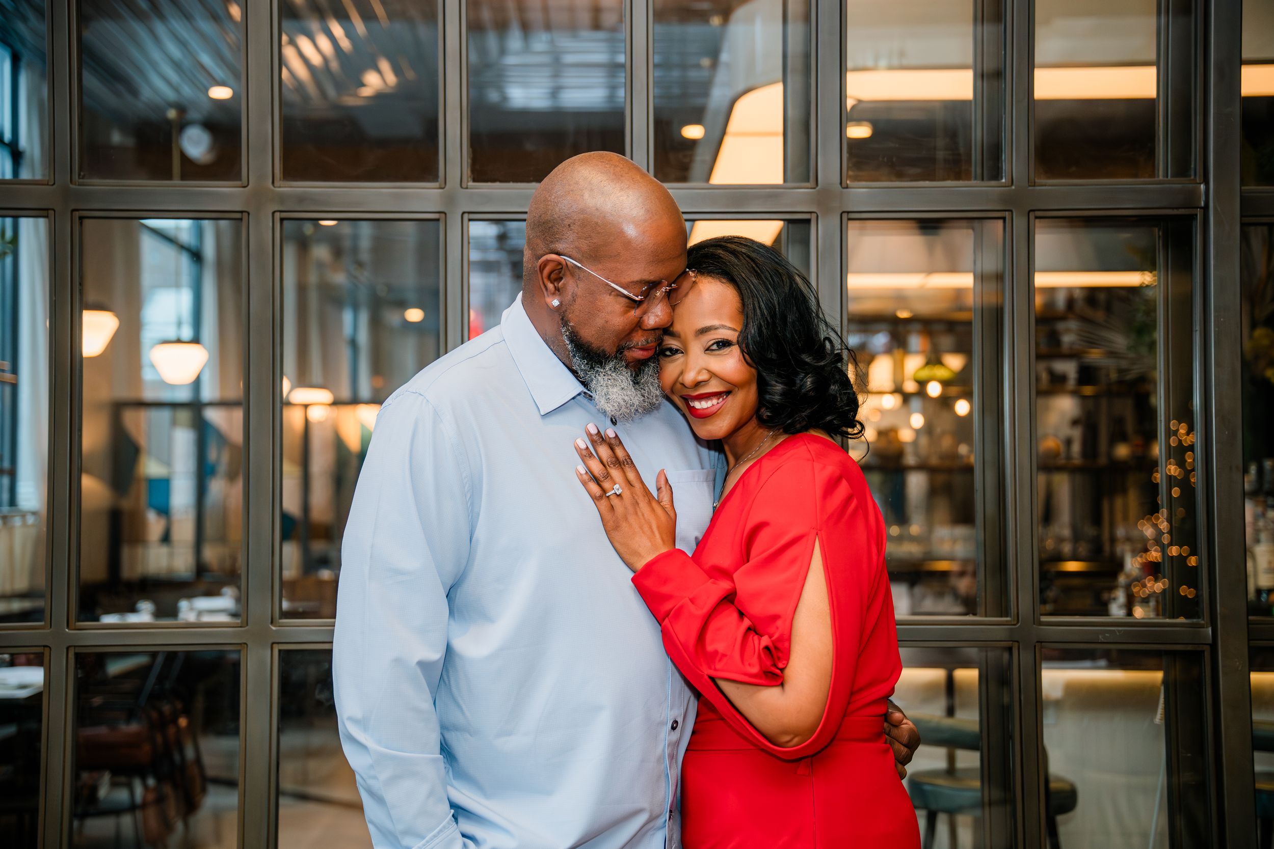 A couple shares a romantic moment together in a bright indoor setting wearing red and light blue outfits in New Haven, CT.