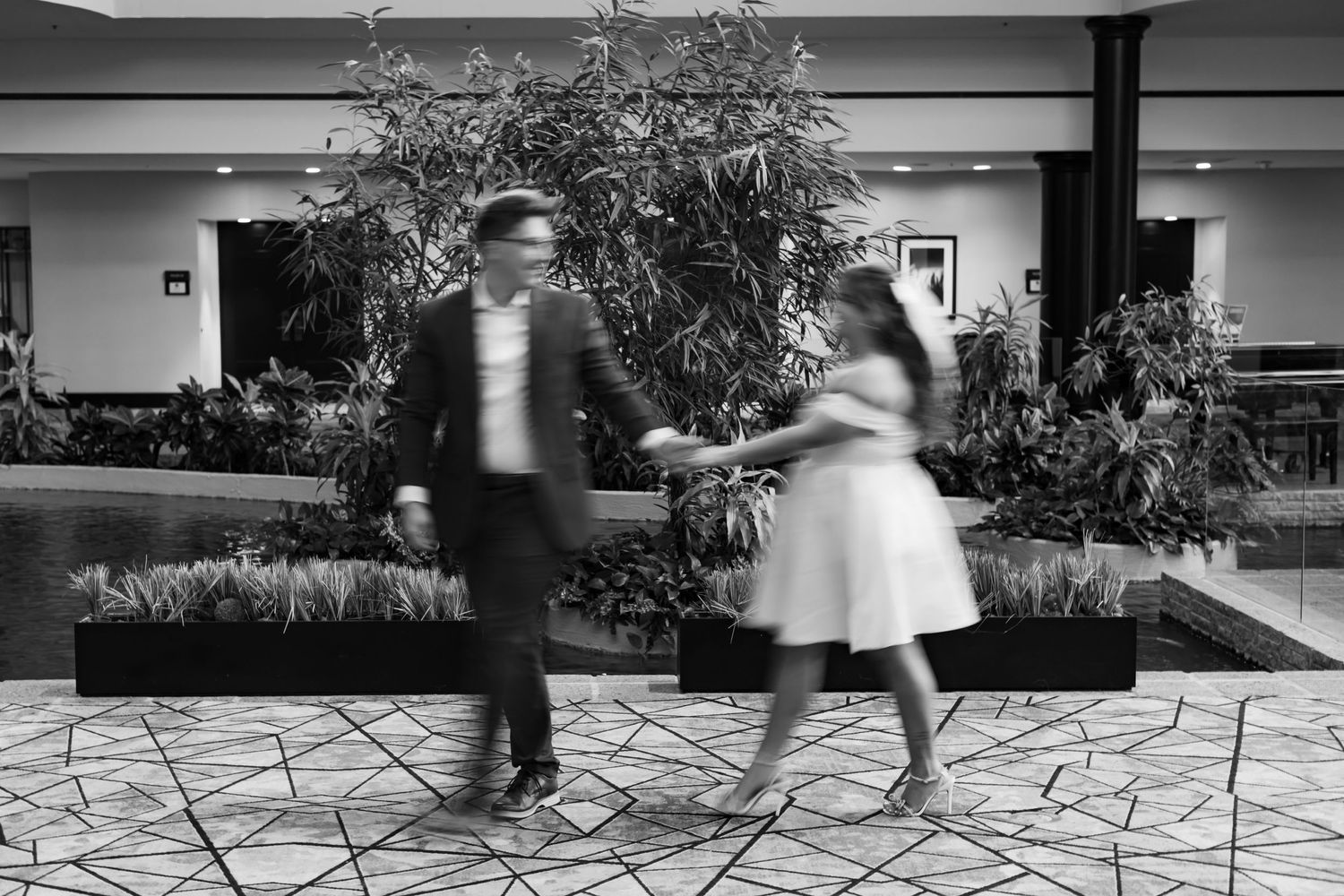 Motion-blurred black and white photograph of a dancing couple on a patterned stone patio.