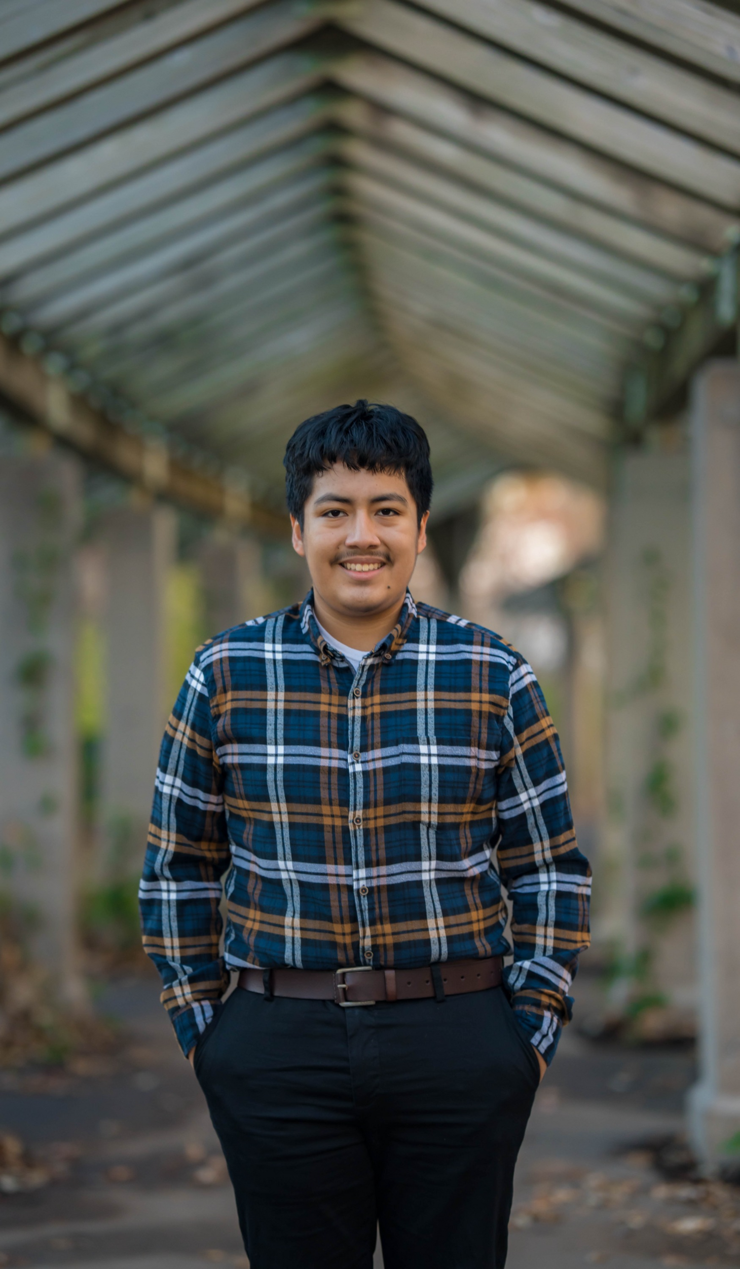 A senior poses confidently for their graduation photo, smiling with pride
