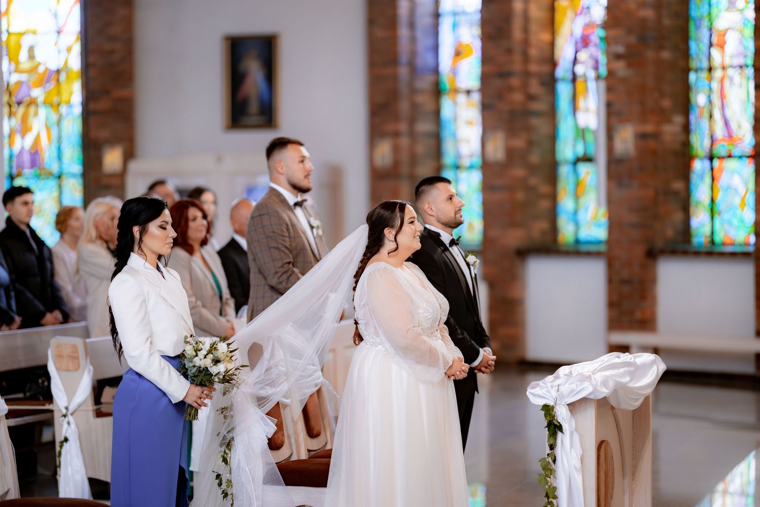 A wedding ceremony in progress inside a beautiful church with stained glass windows.