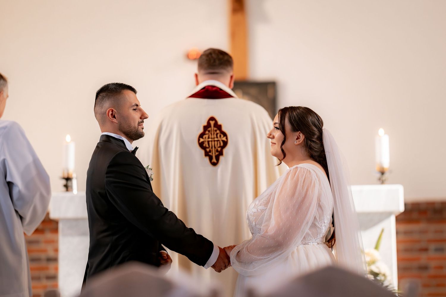 A couple exchanges vows during their wedding ceremony as a priest officiates.