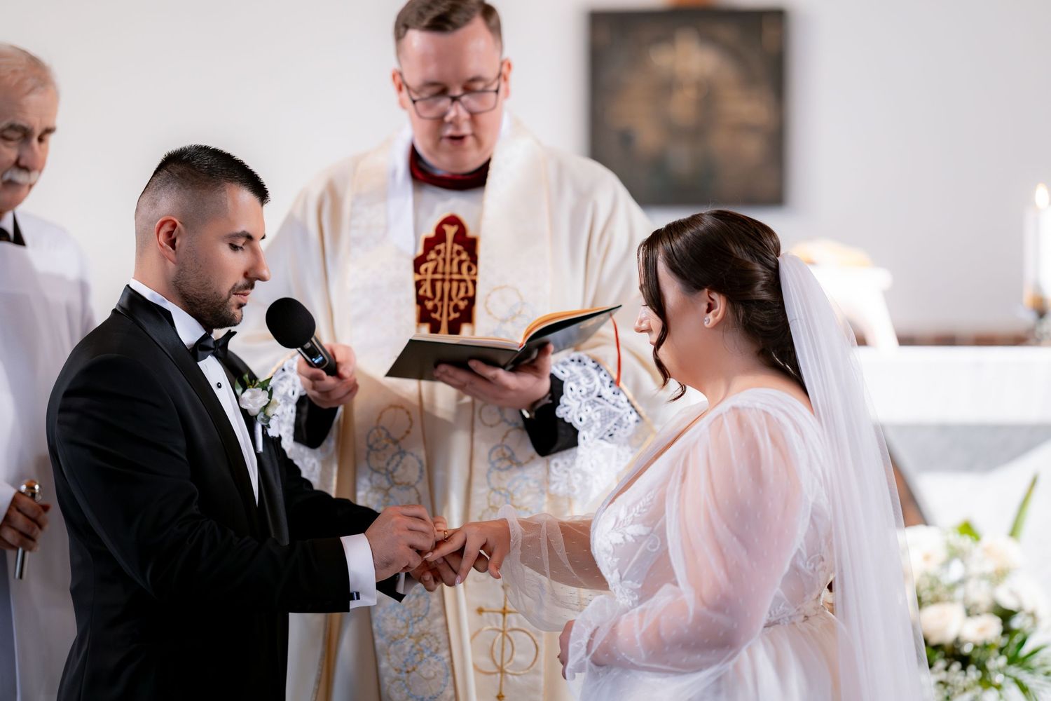 A couple exchanges vows during a traditional church wedding ceremony with a priest officiating.