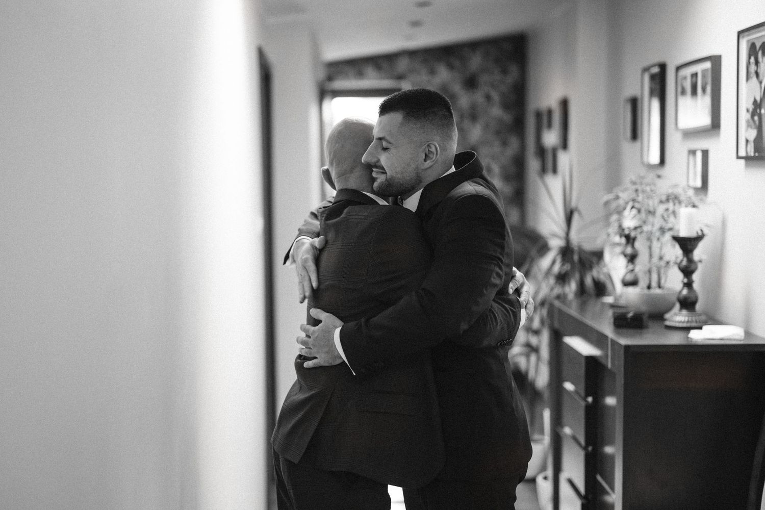 Emotional black and white moment between two people embracing in hallway.