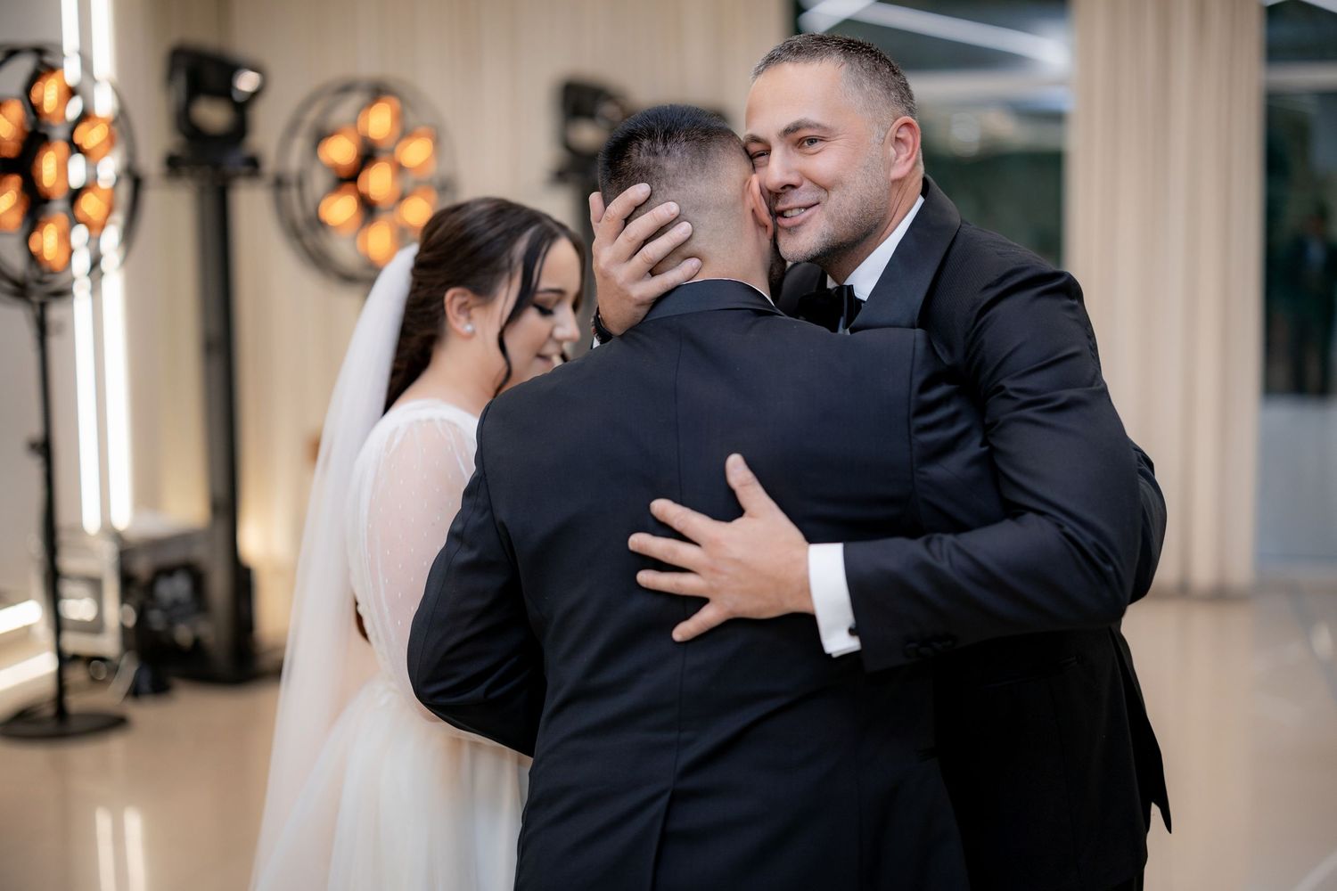 An emotional embrace during a wedding reception with warm lighting and decorative elements.