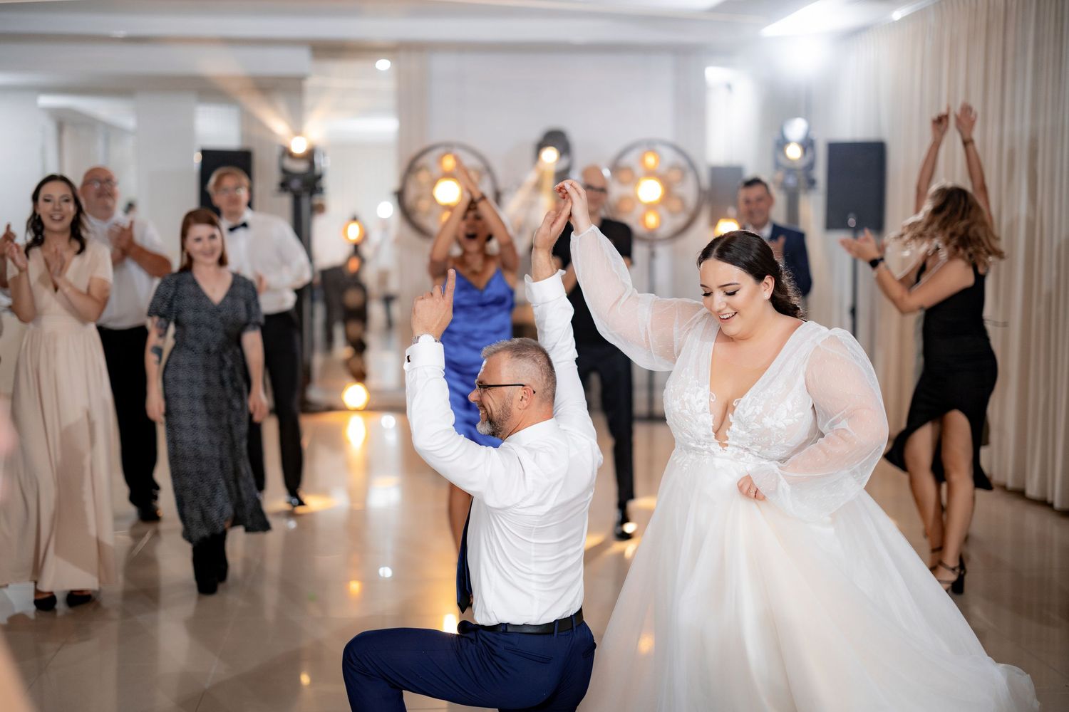 Wedding celebration featuring dancers on the dance floor with decorative lighting.