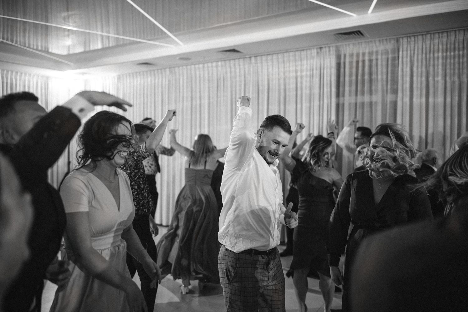 Black and white shot of wedding guests dancing and celebrating on the dance floor.
