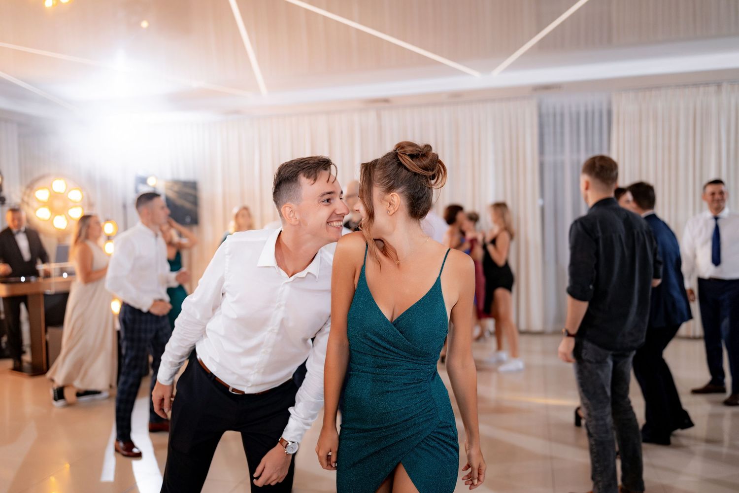Wedding guests dancing together at an elegantly lit indoor reception.