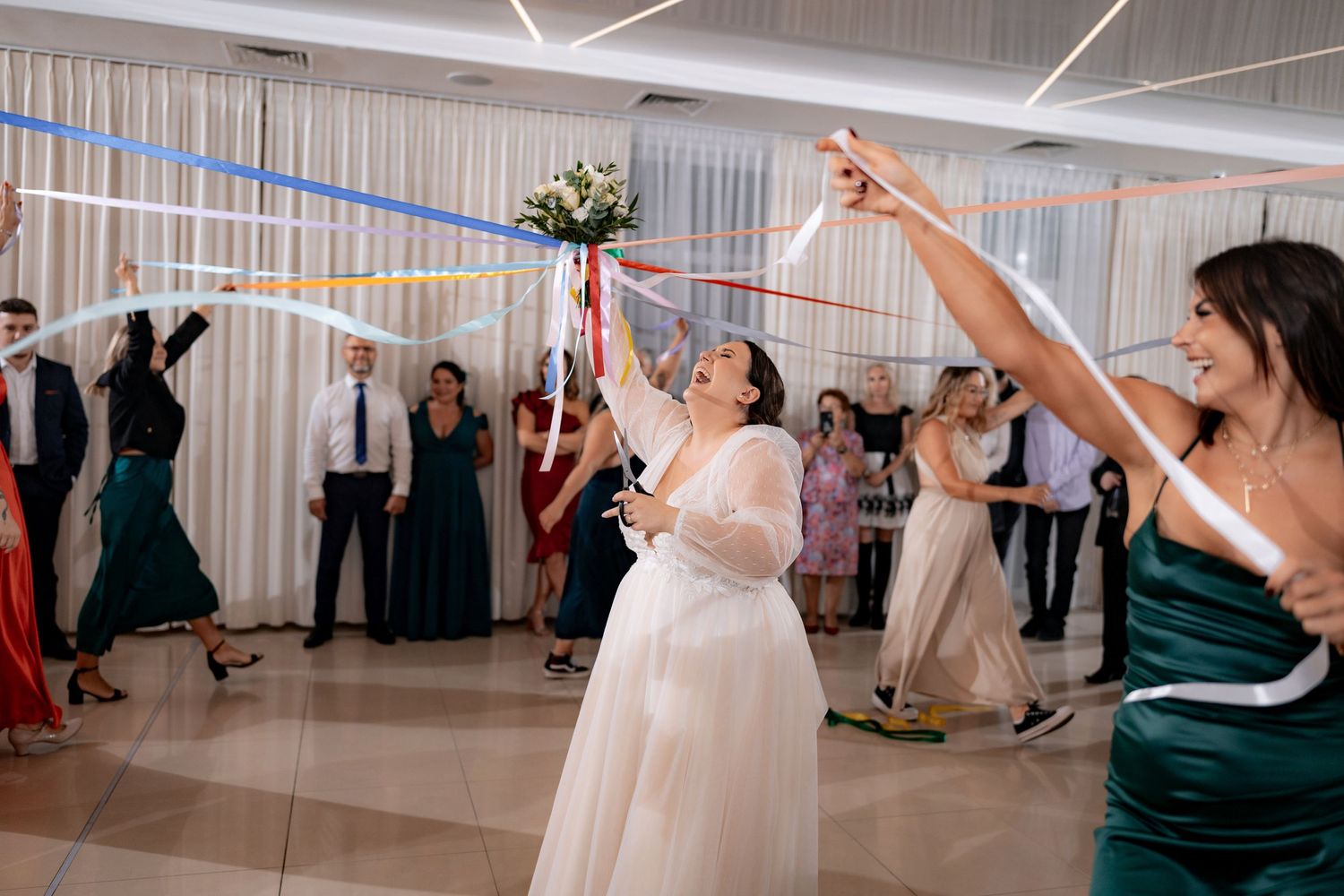 Wedding reception guests celebrate with colorful streamers on the dance floor.