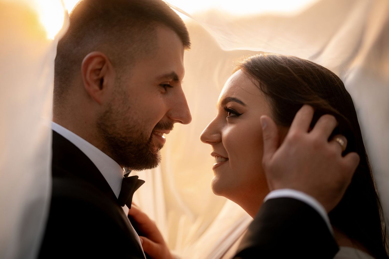 Intimate moment between newlyweds during golden hour with soft lighting and romantic atmosphere.