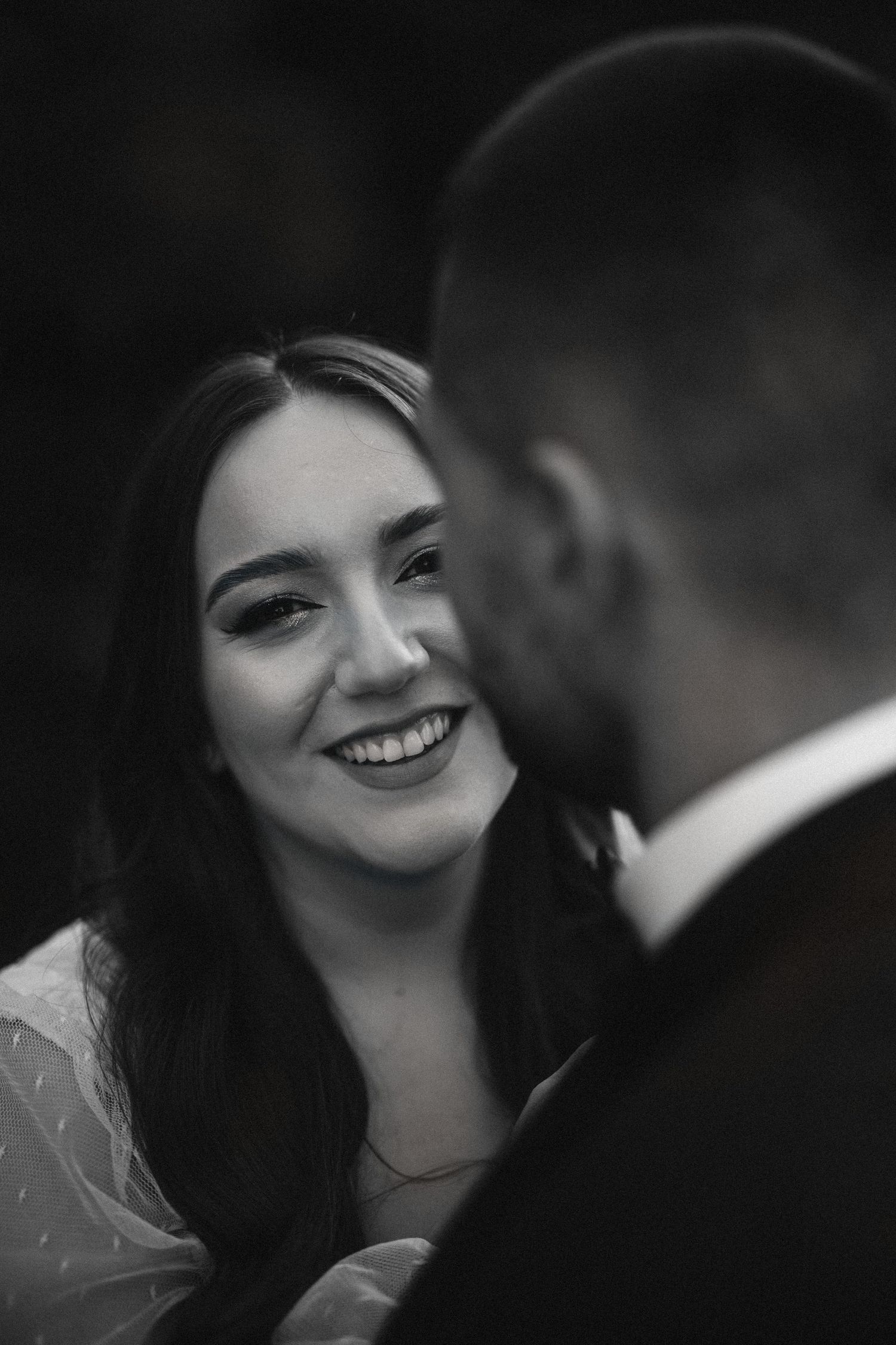 A romantic black and white candid wedding portrait showing a joyful intimate moment between newlyweds.