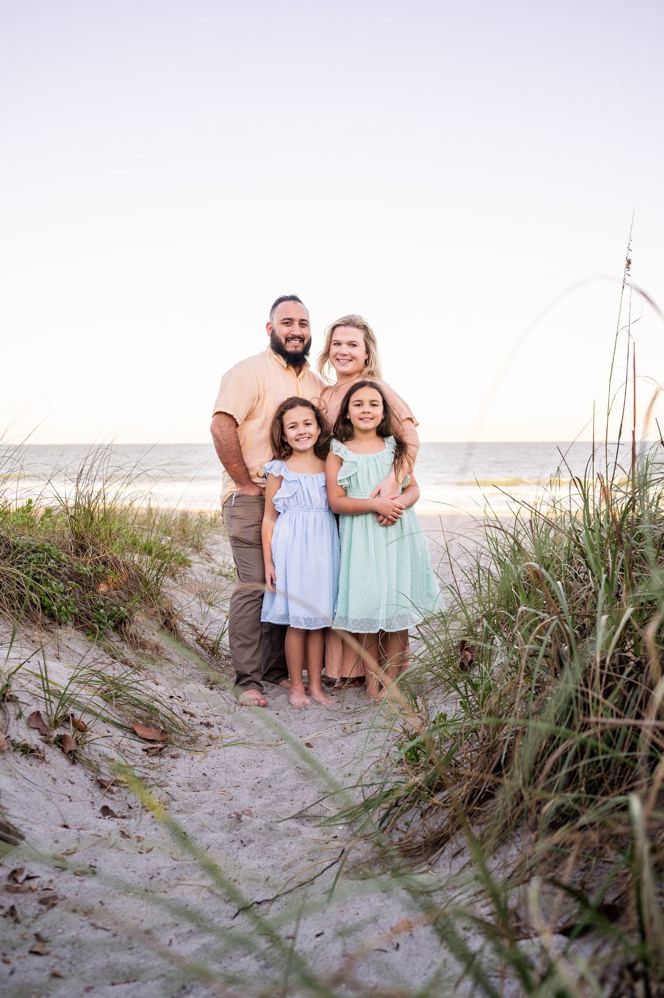 Family portrait photoshoot featuring a smiling mother, father, and a child standing together on a beach Melbourne Cocoa Beach Vero  Florida