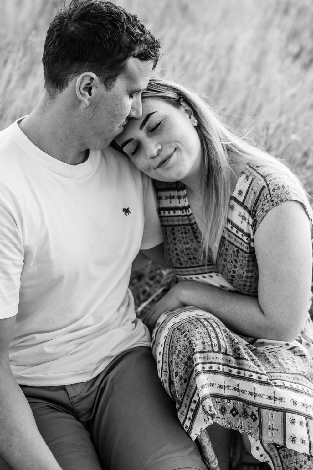 A tender black and white moment captured between a couple in a field.