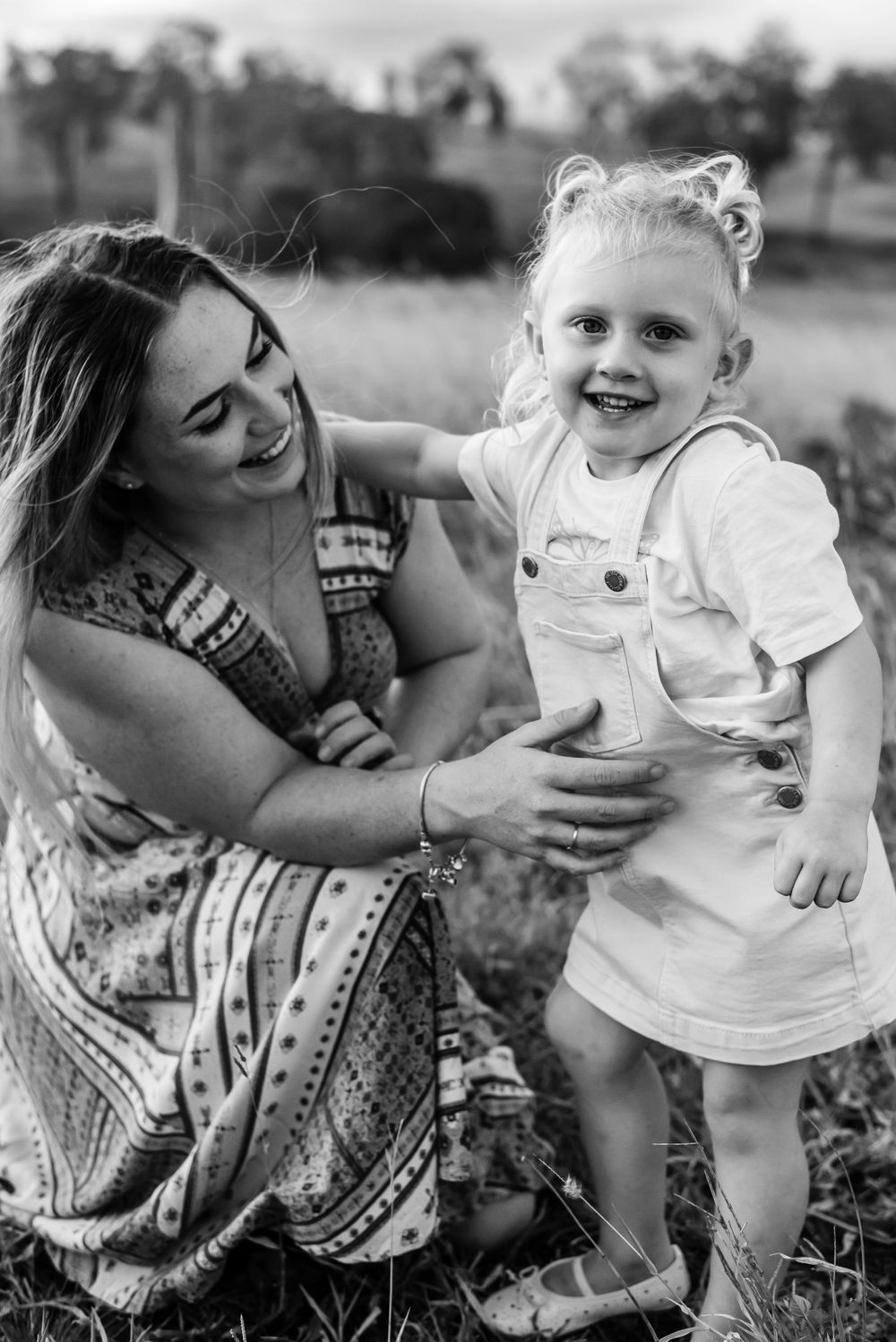 A candid black and white moment catching joyful laughter in an outdoor setting.