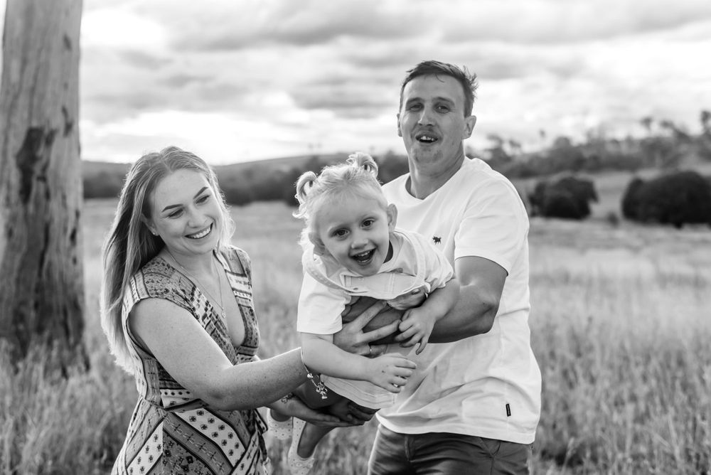 Black and white photo of a family laughing together in an open field.