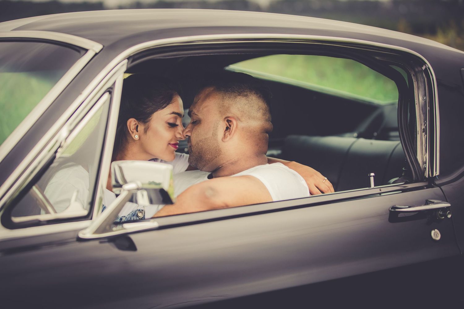 Sri Lankan Tamil Couple posing sitting at the front of a classic mustang facing each other with noses alsmost touching