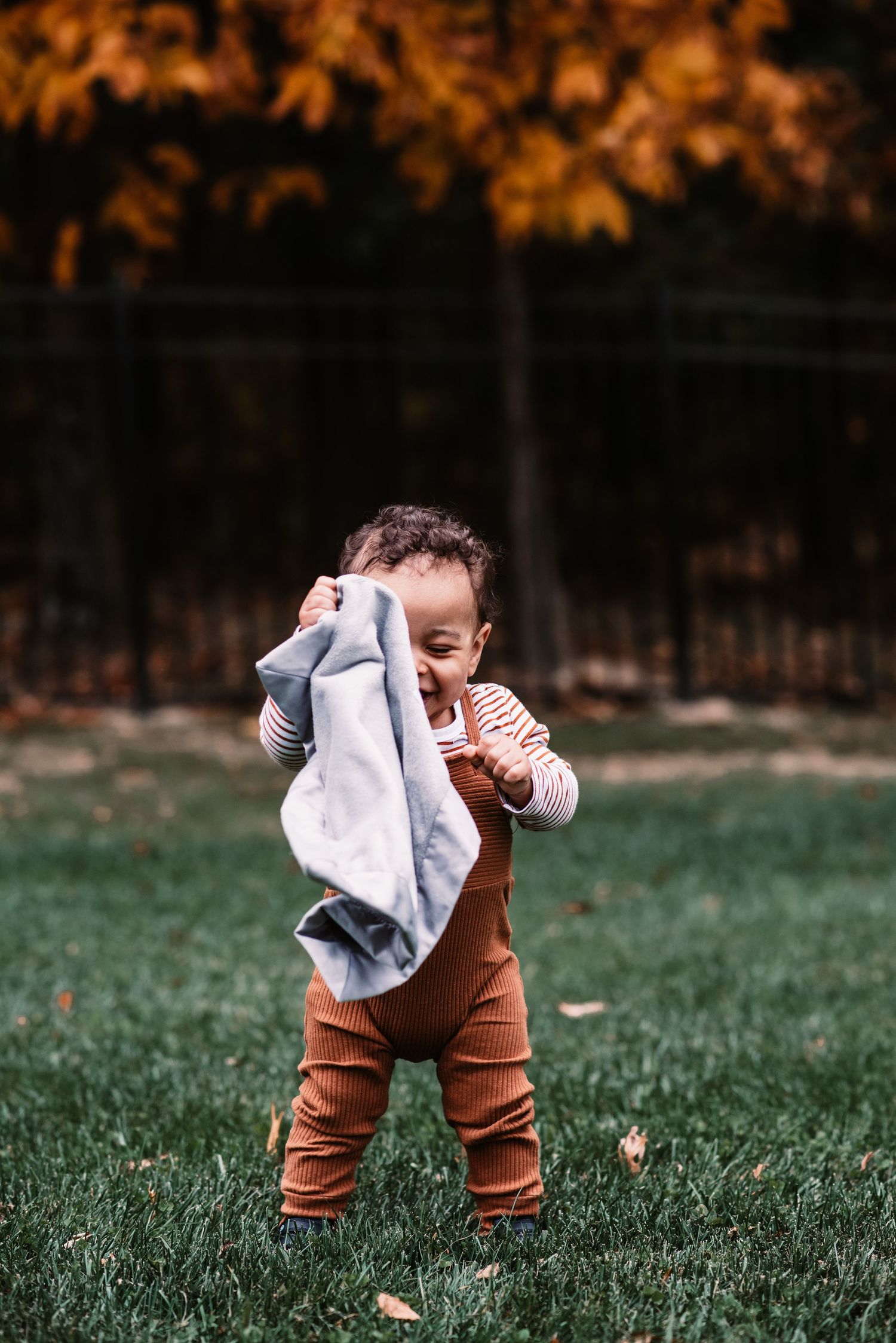 Outdoor photograph of a baby standing with his blanket at home with Autumn colors near Lancaster County PA.