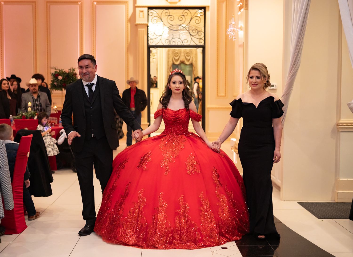 A celebration entrance features a person in a red ball gown accompanied by attendants in formal attire.