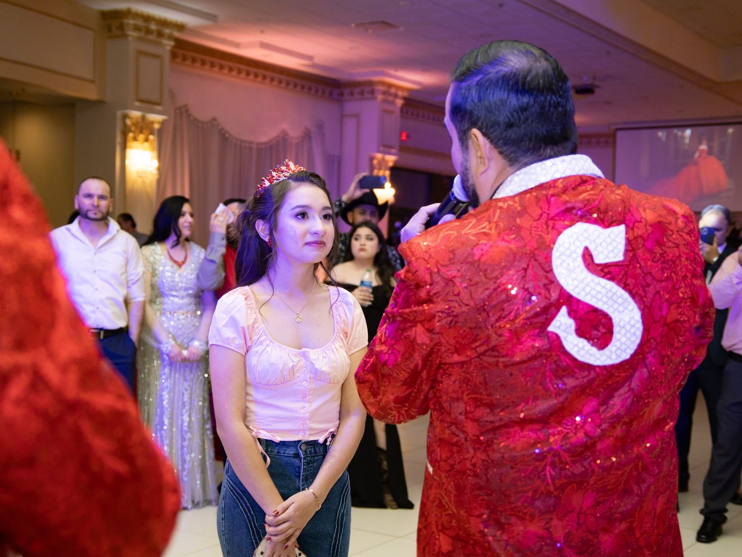 Formal event scene with sparkly red jacket in an elegant ballroom setting.