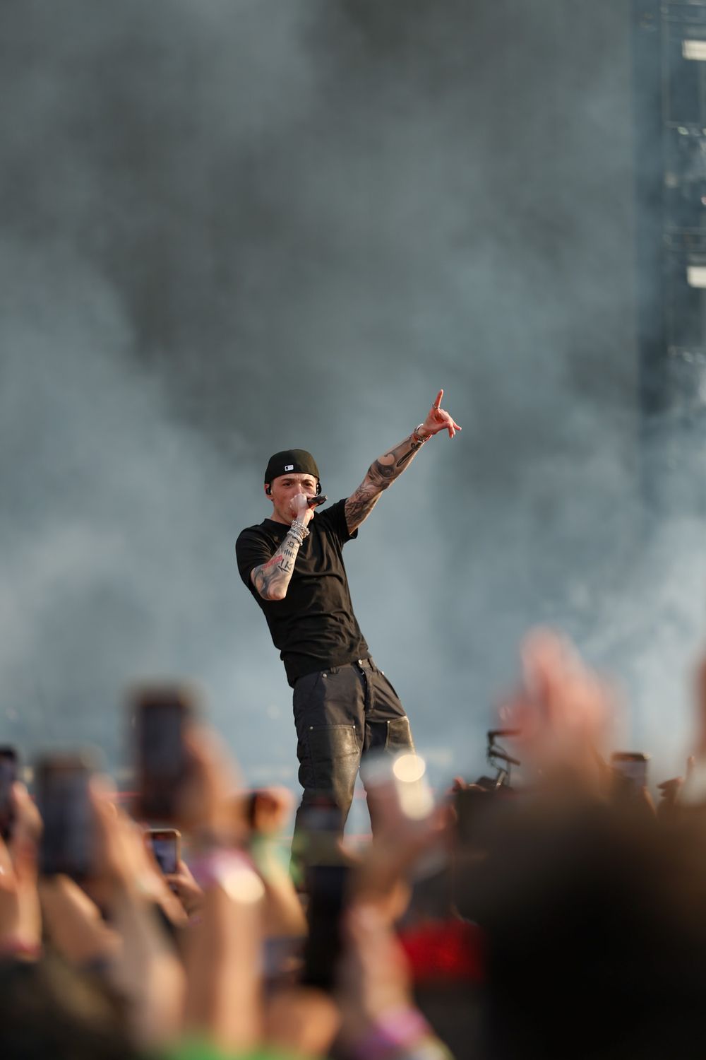 Performer on stage gesturing to crowd through atmospheric smoke effects.