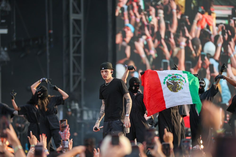 Festival crowd waving Mexican flags during outdoor concert performance.