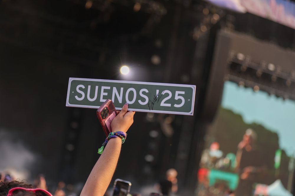Concert stage setup with 'SUENOS 25' sign visible.