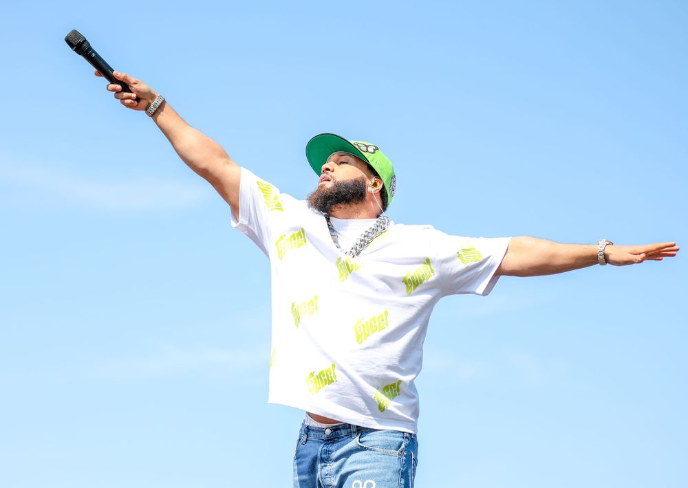 Entertainer with microphone striking dynamic pose against bright blue sky.