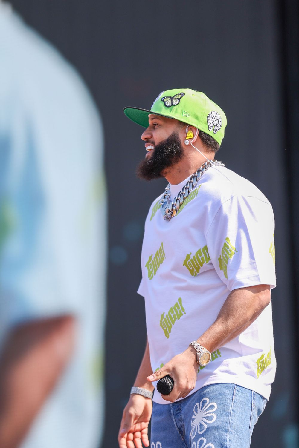 Performer in green cap and white shirt with butterfly motif moving dynamically on stage.