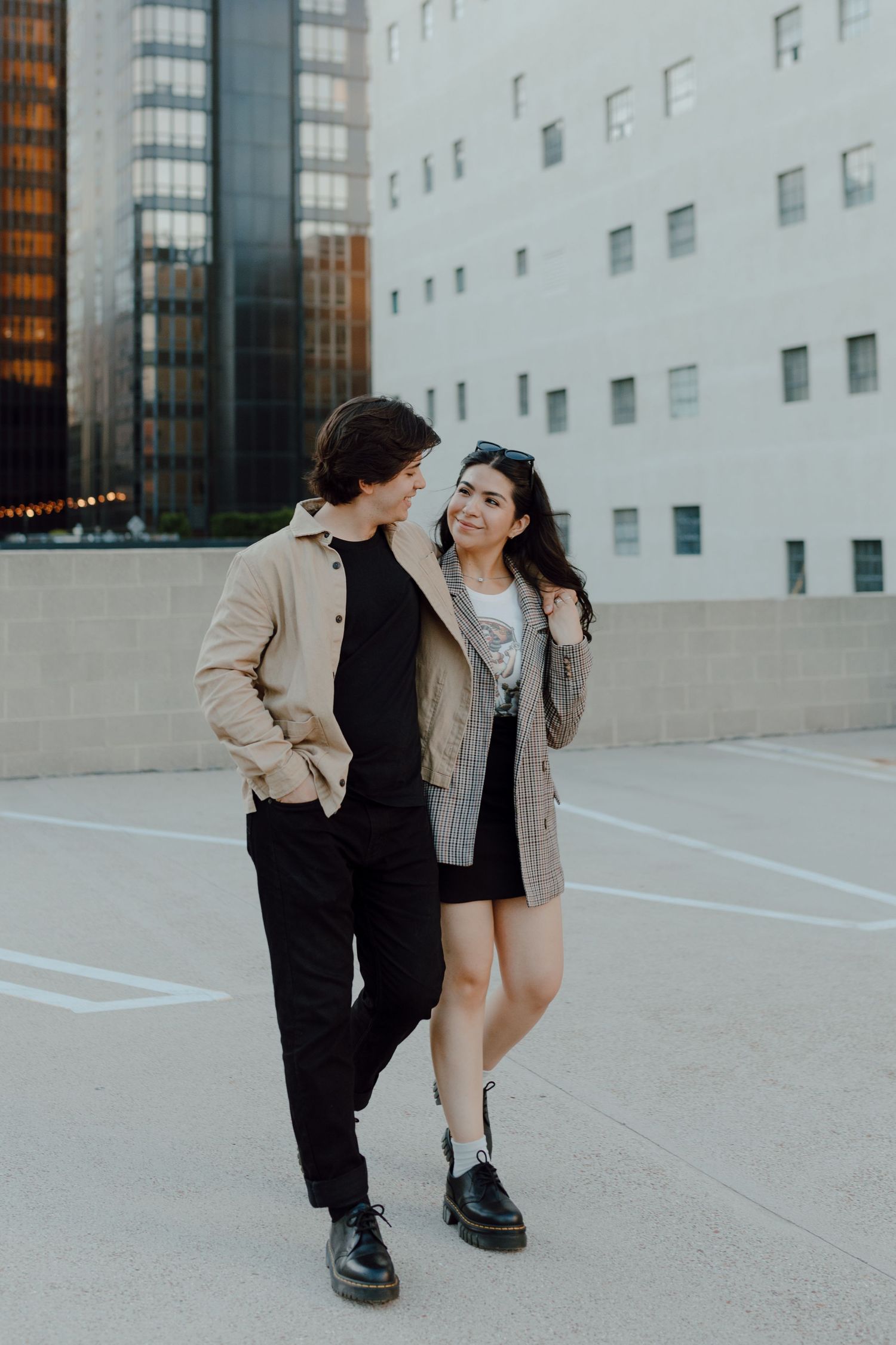 Stylish couple sharing an intimate moment against modern urban architecture at sunset.