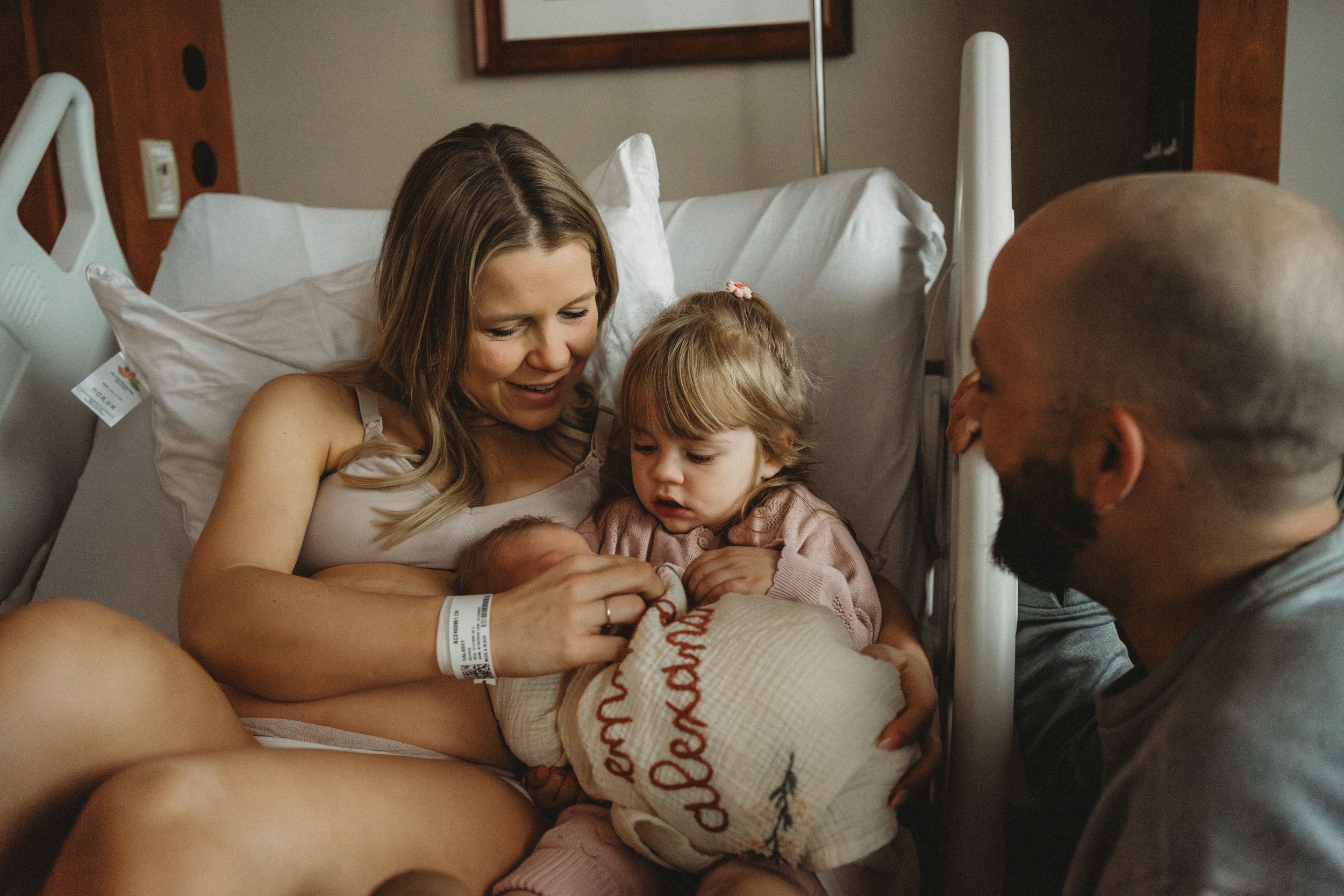 A tender moment shared in a hospital room as a family gathers around a new addition.