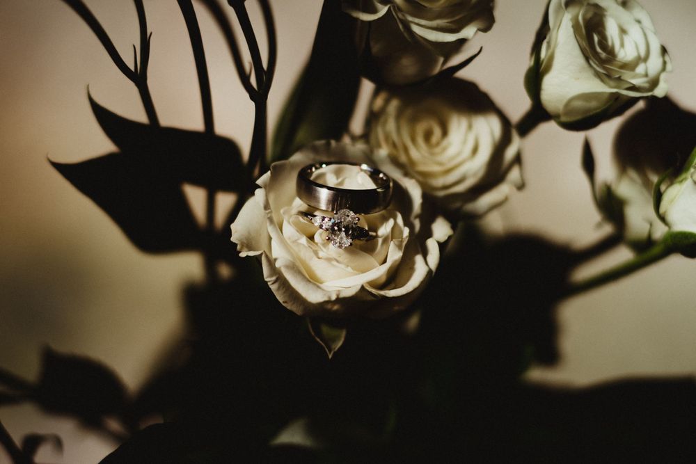 Elegant wedding details with white roses and dark moody lighting creating dramatic shadows.