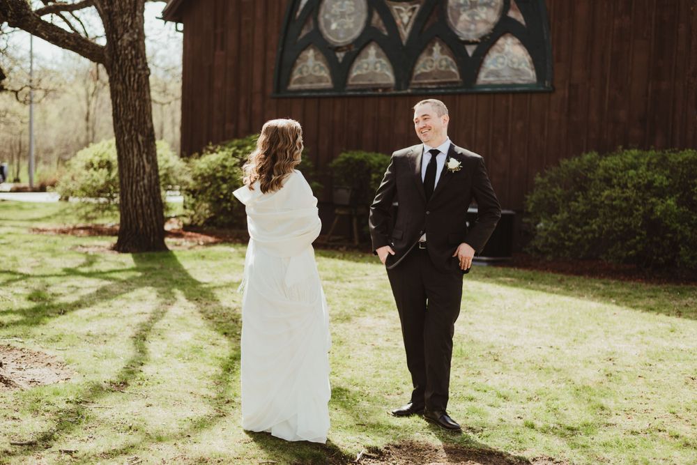 Rustic wooden chapel exterior with gothic windows surrounded by trees.