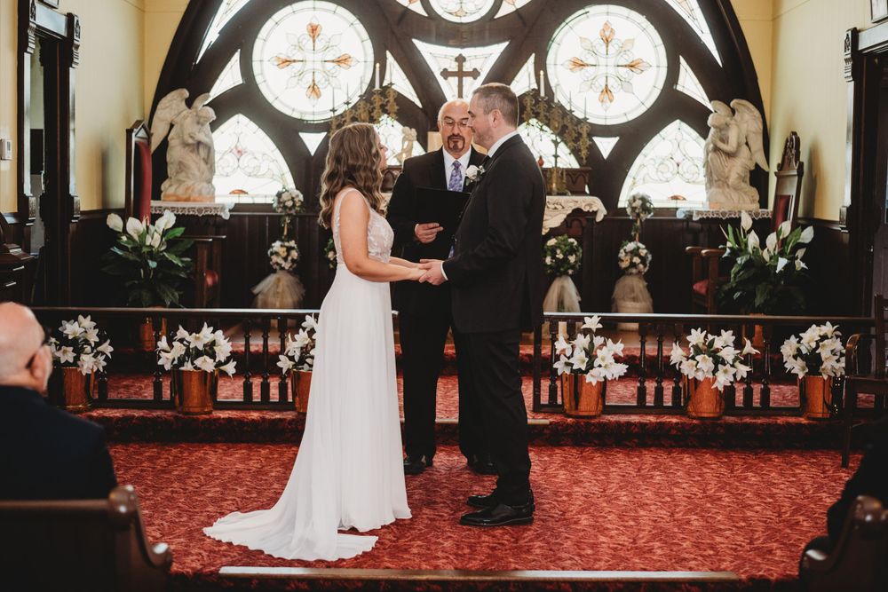 A wedding ceremony taking place in front of an ornate Gothic church altar with decorative crosses.