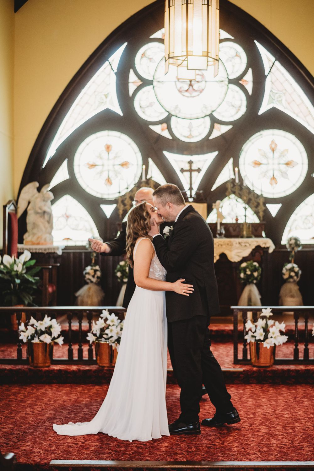 An intimate moment during a church wedding with beautiful Gothic architecture and stained glass in the background.