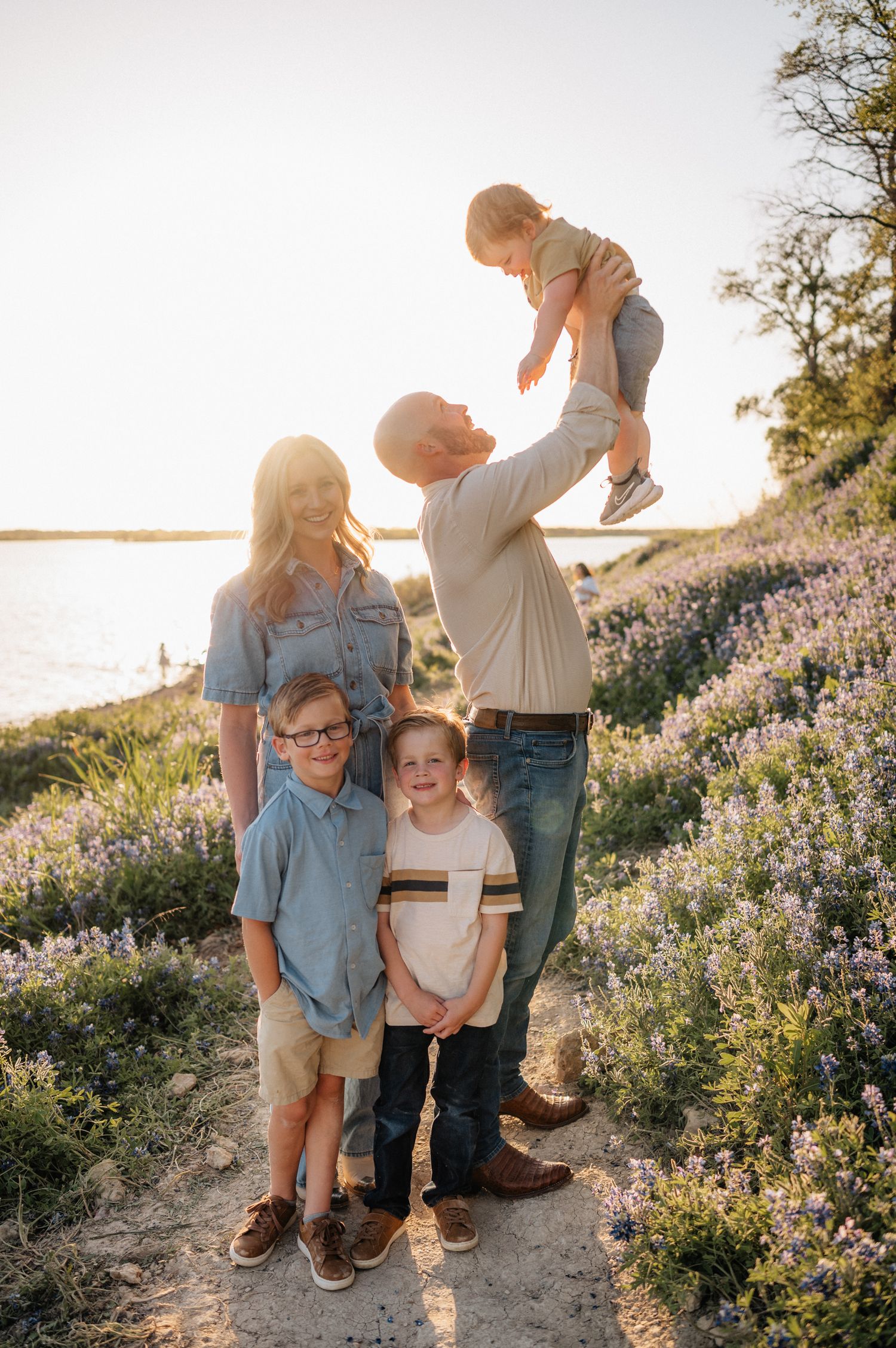 Family poses together in a field of wildflowers at sunset along a coastal hiking trail.