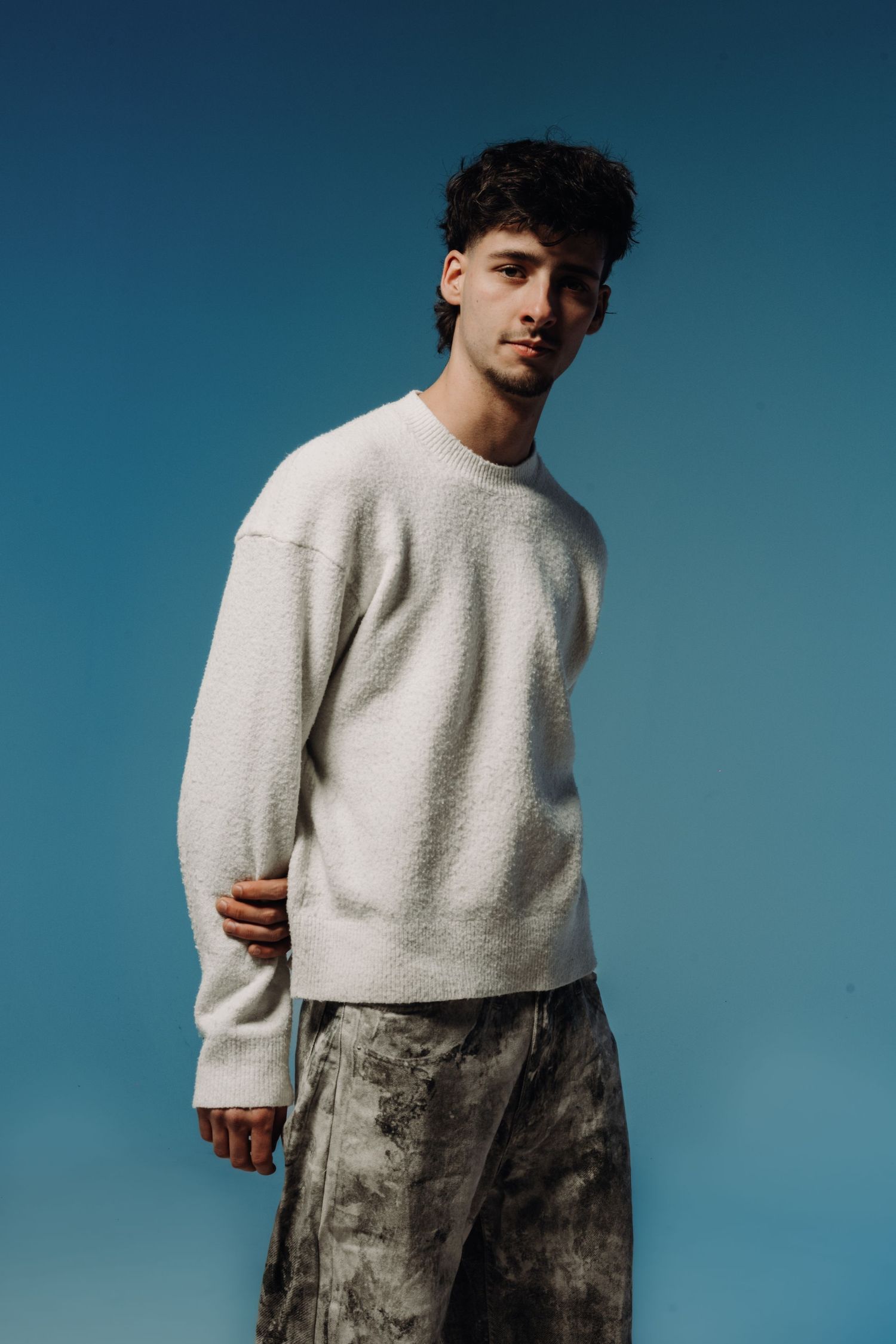 Fashion photo series featuring a light gray sweater against a blue backdrop.