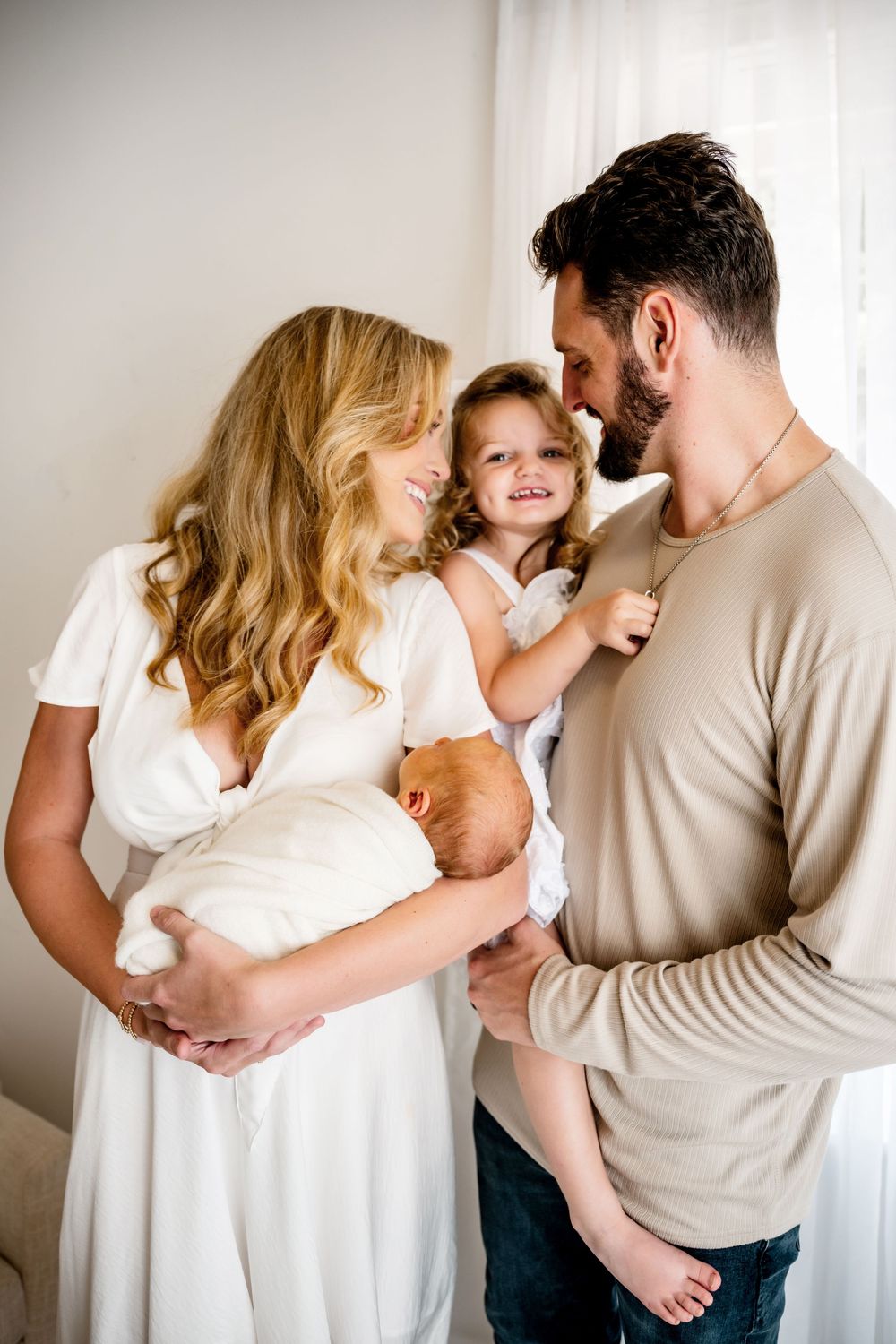 Intimate family portrait series in white and beige tones against light backdrop.