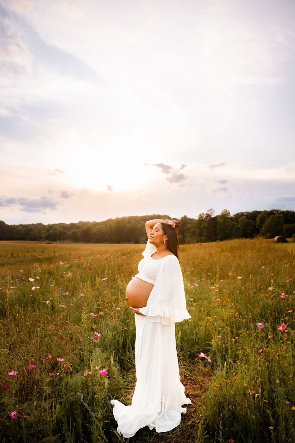 Ethereal maternity photography in a wildflower field at sunset.