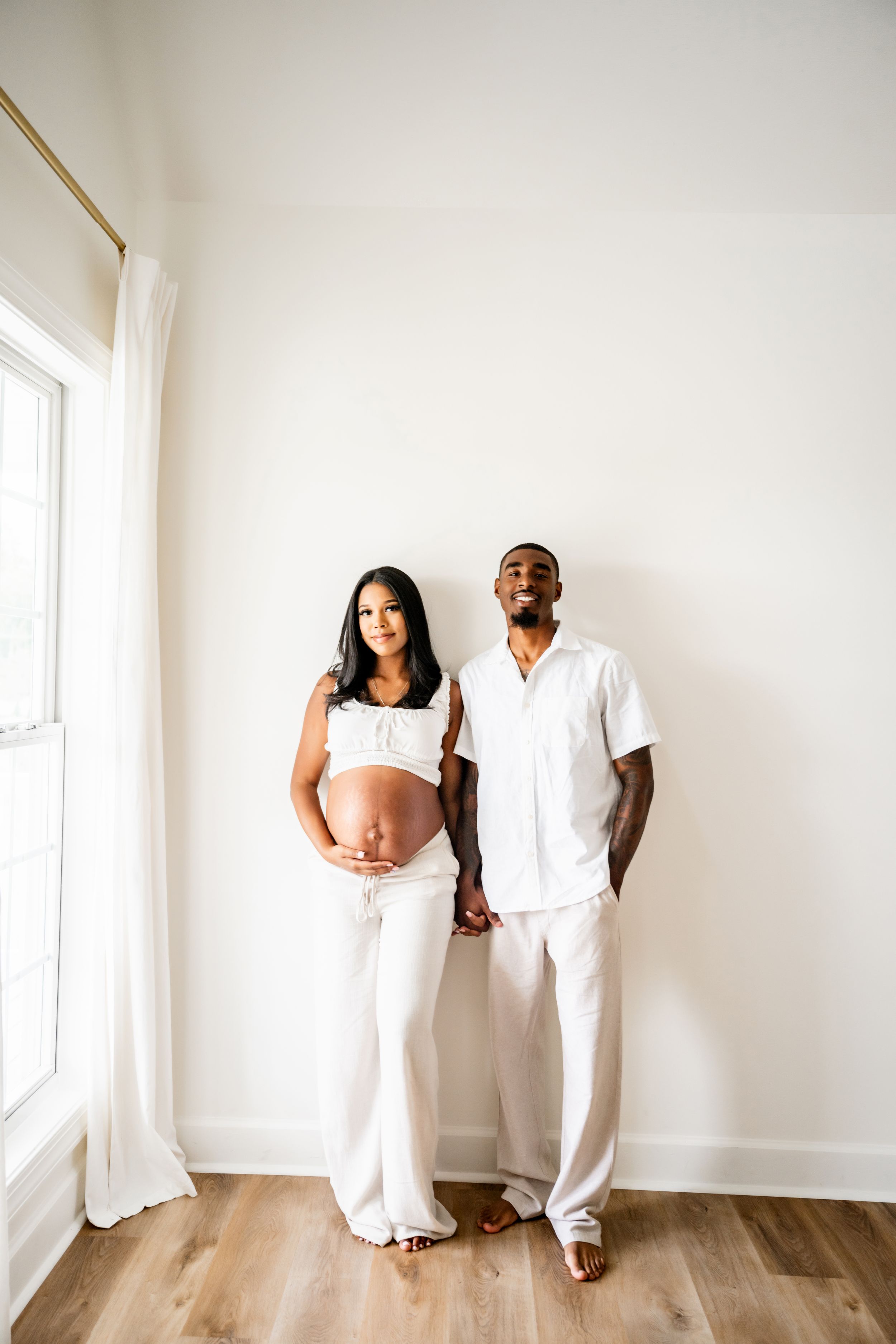 Minimalist family photo session with all-white outfits against white walls.