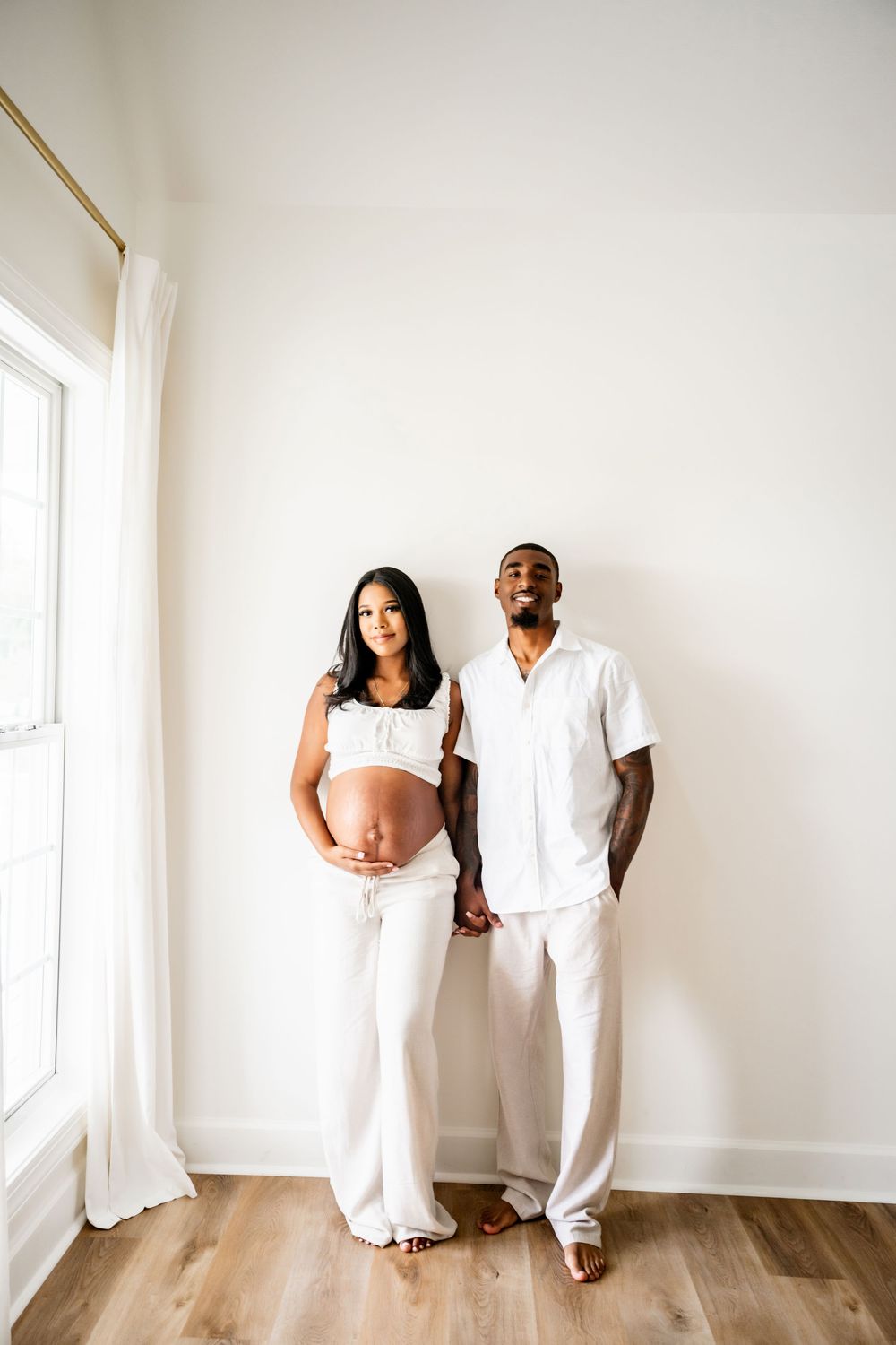 Minimalist family photo session with all-white outfits against white walls.