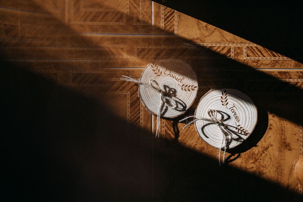 Wedding shoes casting artistic shadows on wooden surface in dramatic lighting.