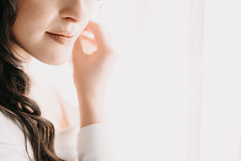 Soft profile portrait of bride with wavy hair bathed in window light.