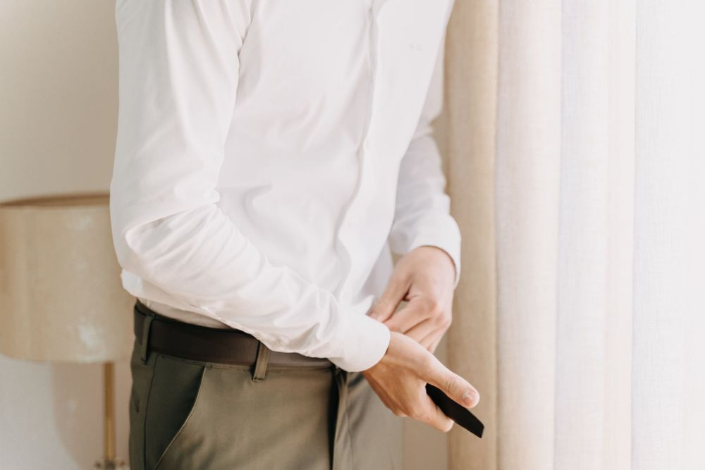 Close up of person holding pen while wearing white shirt and khaki pants.