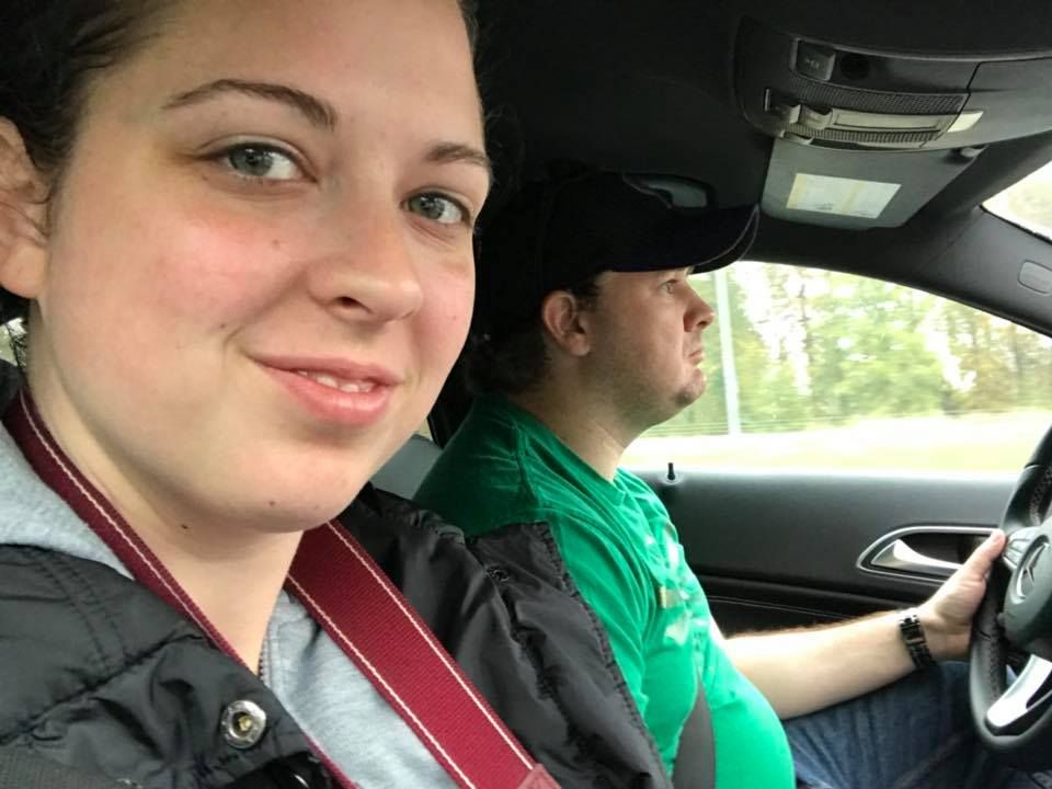 Two people sitting in the front seats of a car during a daytime drive.