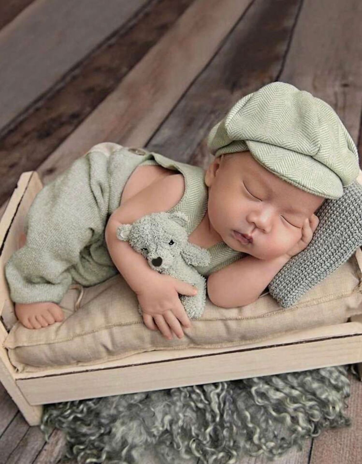 Sleeping figure in mint green outfit with matching cap on textured backdrop.