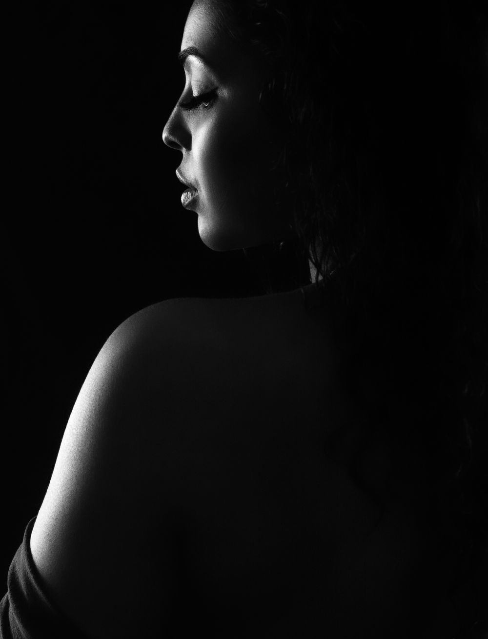 Dramatic black and white profile silhouette highlighting contours and shadows.
