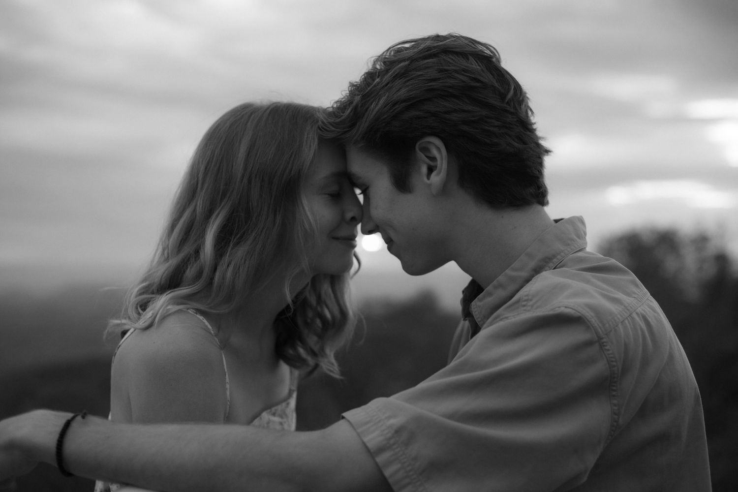 Black and white series of romantic silhouettes showing couple embracing against dramatic sunset sky at beach.